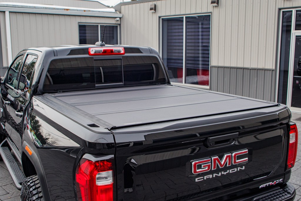 A 2025 GMC Canyon AT4X with a hard tri-fold bed cover, a 4" Rough Country lift kit, 20x9 Fuel Flux wheels, and 35" Avix Trailtek R/T tires.
